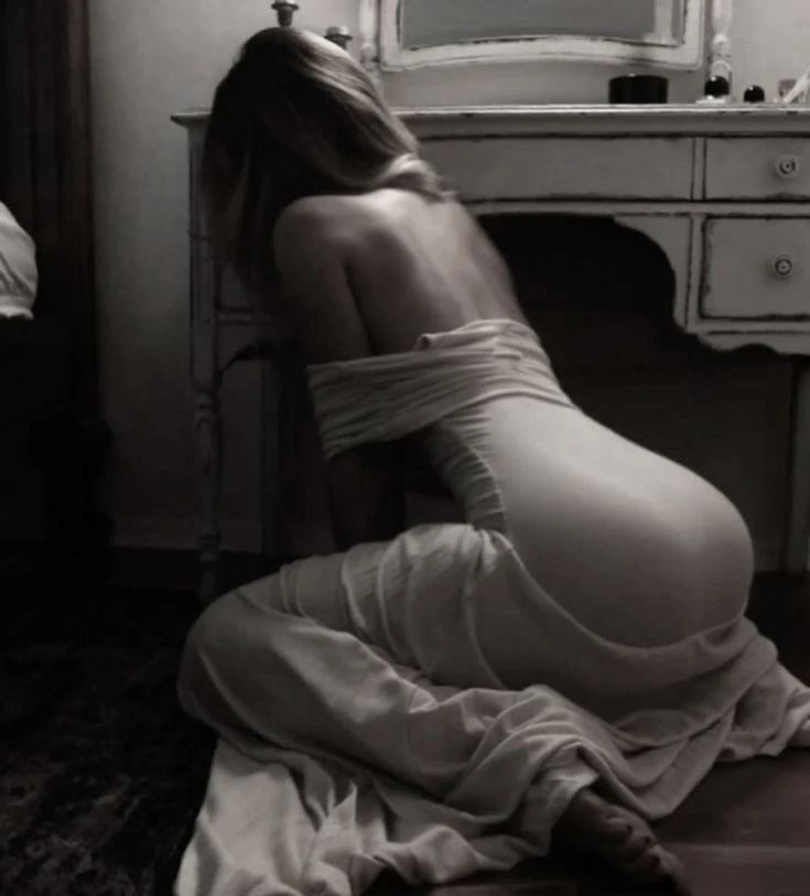 In a dimly lit bedroom, a woman in a lace nightgown is leaning forward, kneeling on the floor. In a dimly lit bedroom, a woman in a lace nightgown is leaning forward, kneeling on the floor.