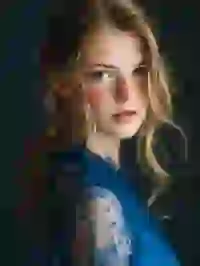 beautiful-blonde-woman-in-blue-sheer-dress Portrait of a blonde woman with low ponytail and freckles staring at the camera. Template for Undress AI.