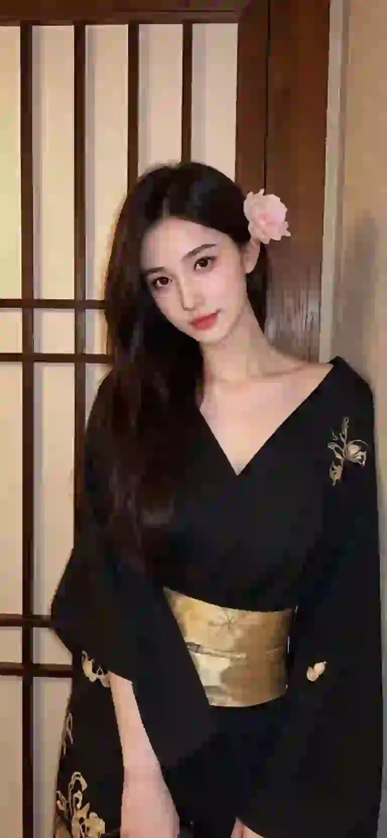 Asian woman in black kimono posing in a Japanese style room.