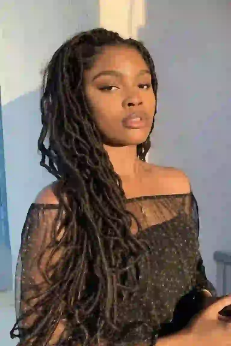 Black woman in black sheer dress posing outdoors.