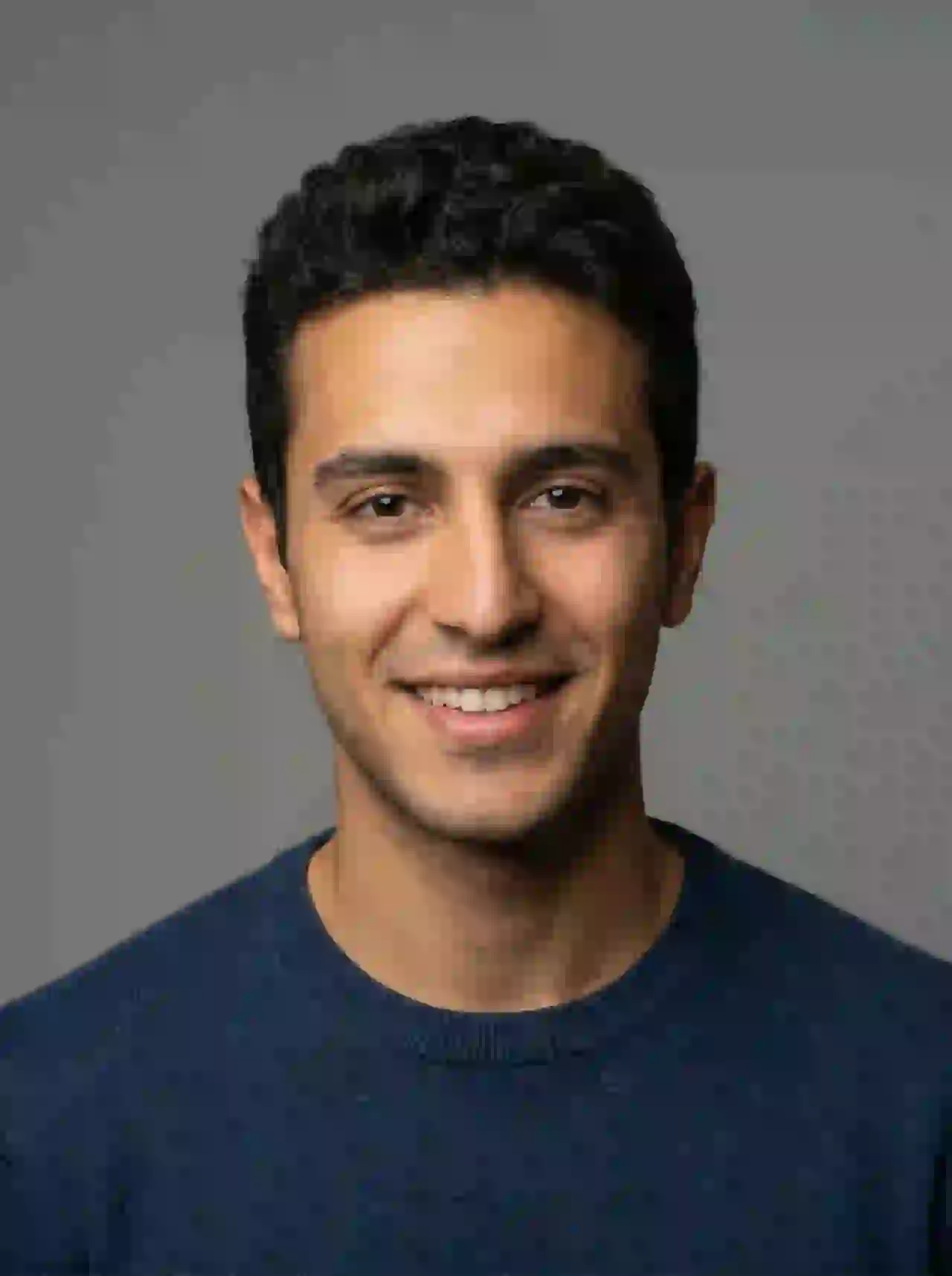 Arab man with short dark hair and friendly smile in studio portrait. Template for photo face swap.